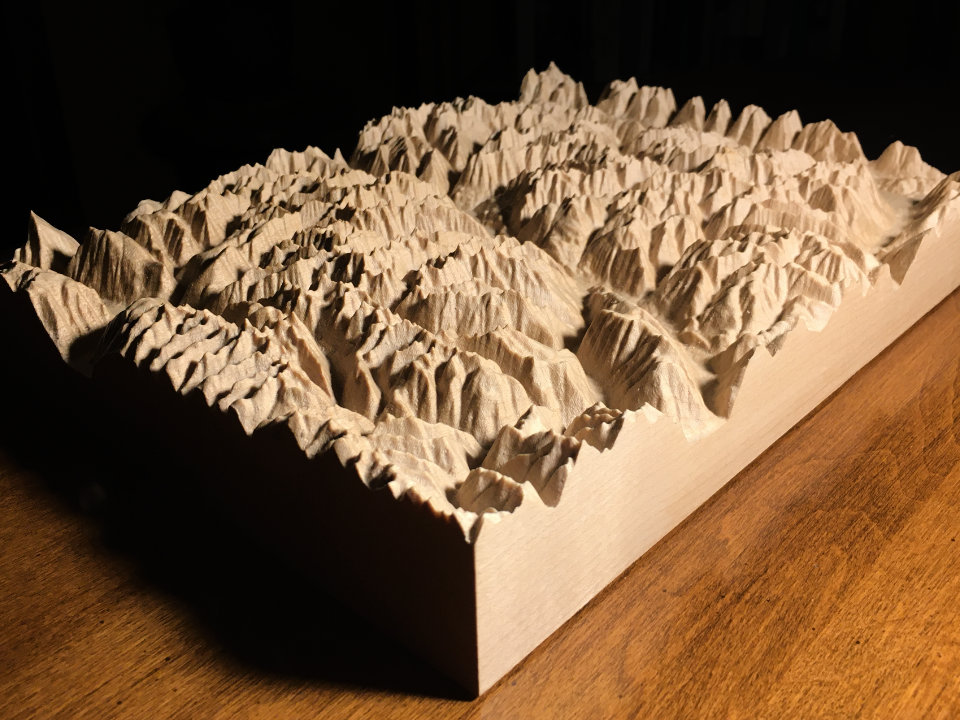 three-dimensional wood-carved relief map of a rectangle of mountains