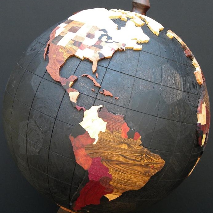 wooden globe made from hexagonal and pentagonal pieces with black oceans and coloured states and countries